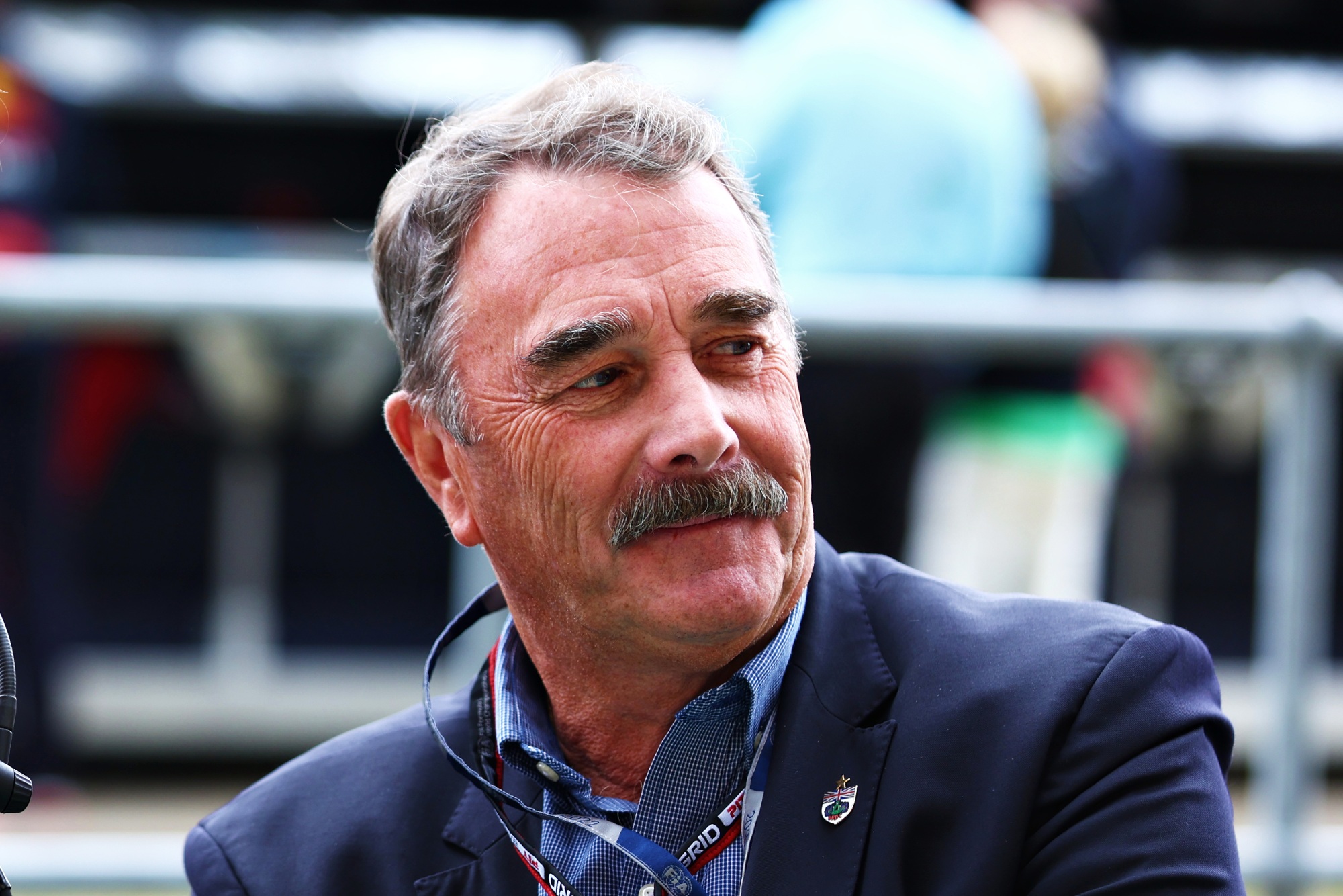 Nigel Mansell, de bigode e terno, olhando para o lado direito