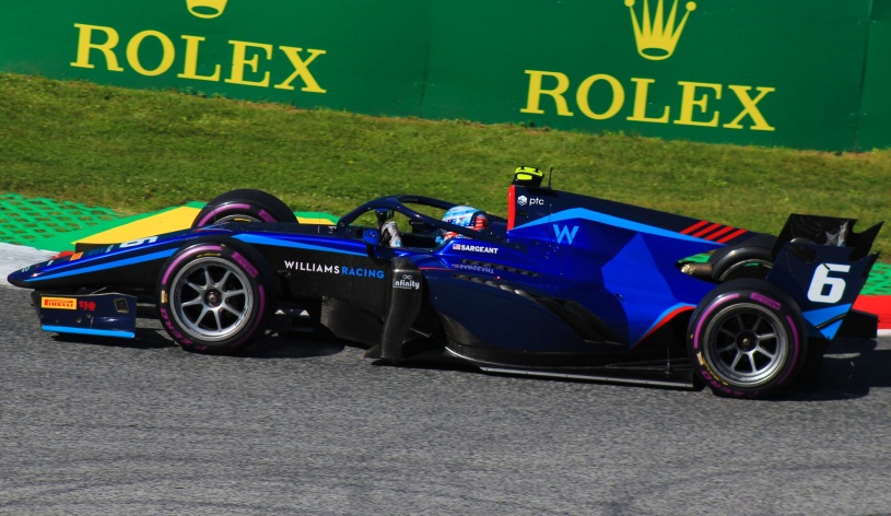 Carro azul e preto, com número 6 na lateral, de Logan Sargeant na F2 visto de lateral